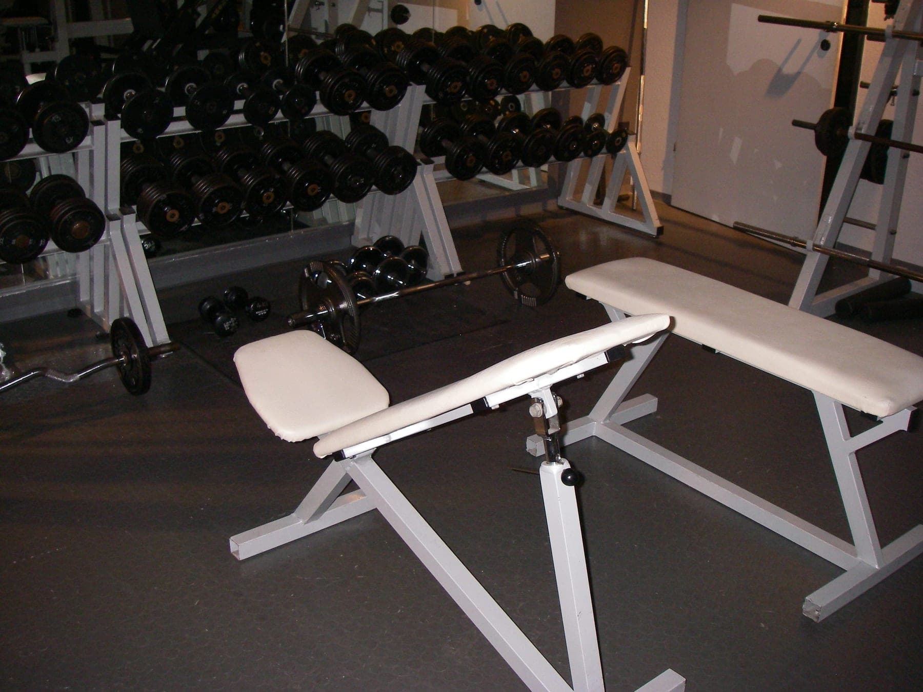 Two weight training benches in a dim training room.